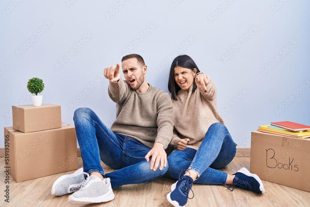 Young couple moving to a new home pointing displeased and frustrated to the camera, angry and furious with you Young couple moving to a new home pointing displeased and frustrated to the camera, angry and furious with you