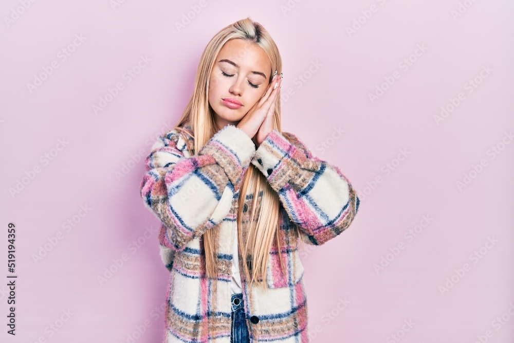 Young blonde girl wearing casual clothes sleeping tired dreaming and posing with hands together while smiling with closed eyes.