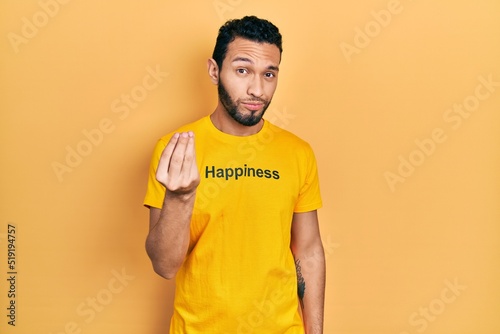 Hispanic man with beard wearing t shirt with happiness word message doing italian gesture with hand and fingers confident expression