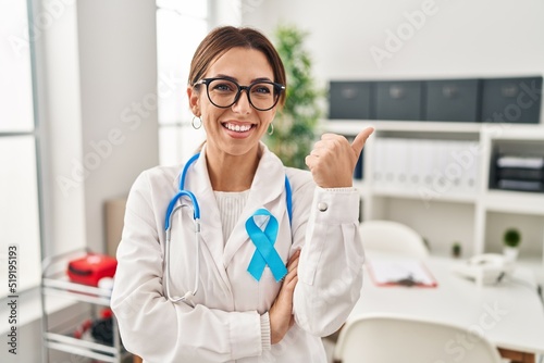 Young brunette doctor woman wearing stethoscope at the clinic with a big smile on face  pointing with hand and finger to the side looking at the camera.