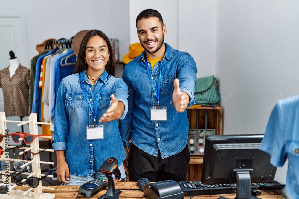 Young interracial people working at retail boutique smiling friendly offering handshake as greeting and welcoming. successful business. Young interracial people working at retail boutique smiling friendly offering handshake as greeting and welcoming. successful business.