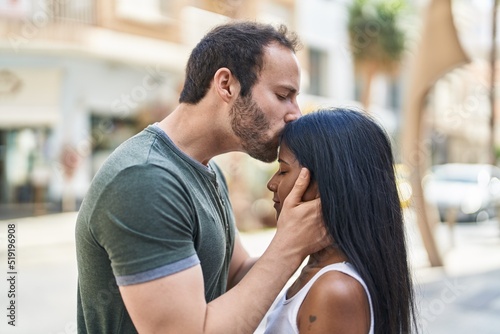Man and woman interracial couple hugging each other and kissing at street © Krakenimages.com