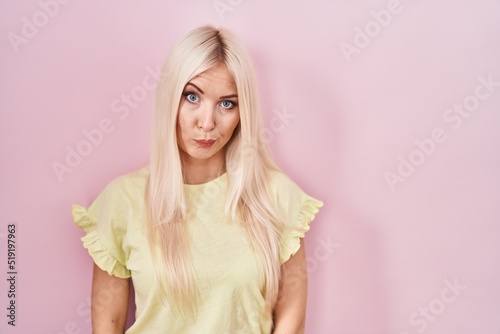 Caucasian woman standing over pink background skeptic and nervous, frowning upset because of problem. negative person.