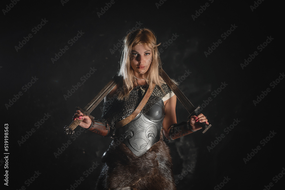 Warrior woman in the armor stands with the two swords in the hands ...