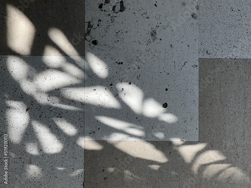 Pattern of shadows cast by sunlight through plants on a grungy, tiled floor, creating abstract background