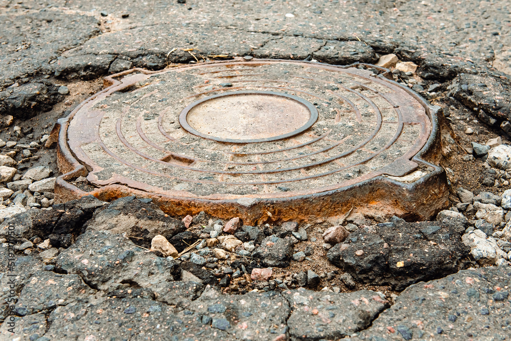 Sewer manhole on an old broken asphalt road. Road works