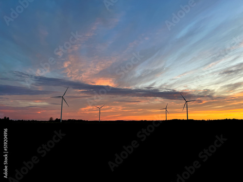 Orange sunset with purple cloud in the landscape, black silhouette of the windmills