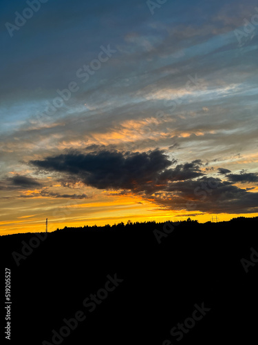 Orange sunset with purple cloud in the landscape, black silhouette of the windmills