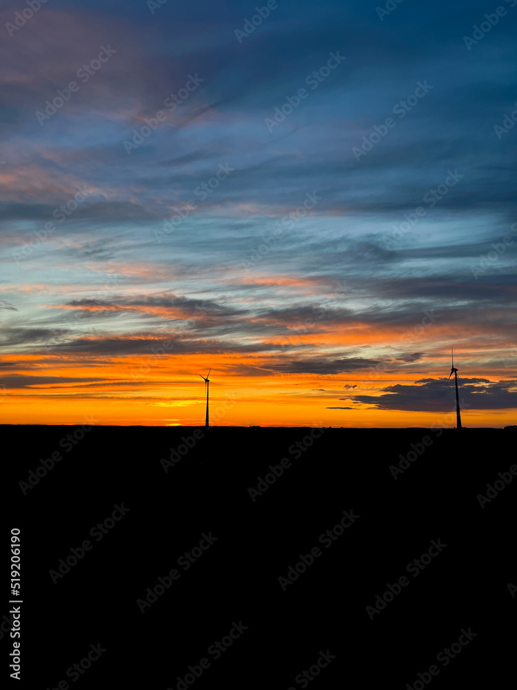 Orange sunset with purple cloud in the landscape, black silhouette of the windmills