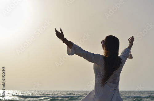 happy young woman enjoying freedom with open hands on sea side