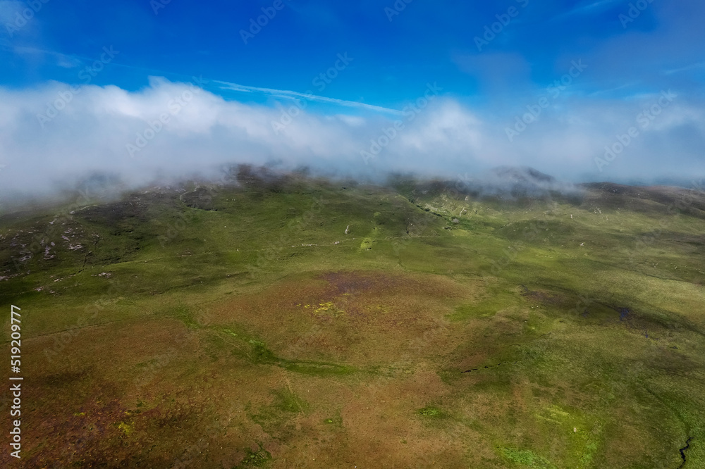 Aerial view on a mountain and green field and turf bog. Connemara, Ireland. Irish landscape and country side. Blue cloudy sky over mountain peak