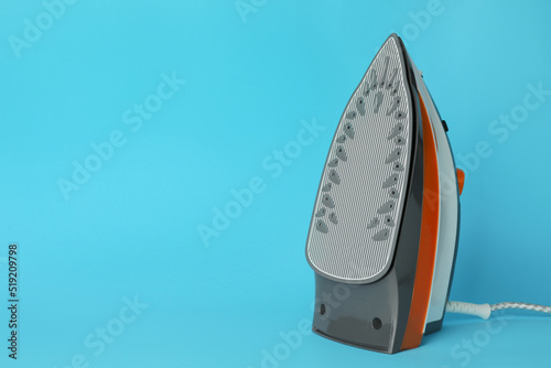 One modern iron on light blue background, space for text. Home appliance