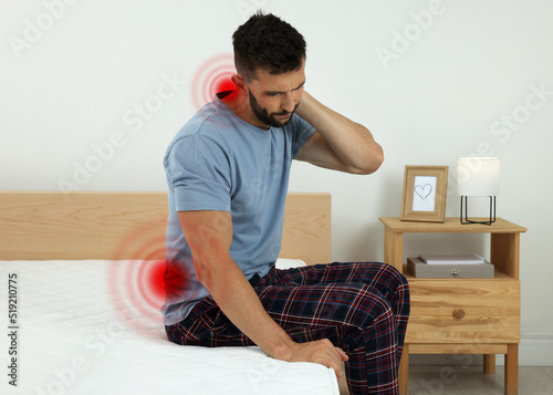 Man suffering from neck pain after sleeping on uncomfortable mattress at home