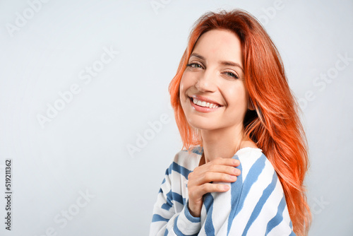 Beautiful woman with long orange hair on light background, space for text