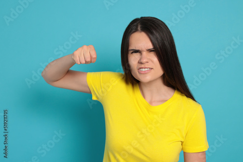 Young woman ready to fight on light blue background