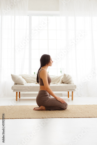 Side view of brunette woman meditating in living room 