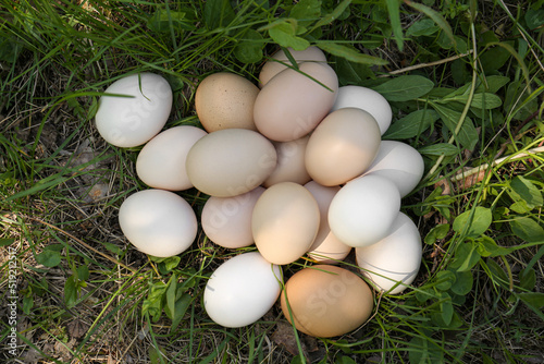 Pile of fresh raw eggs on green grass outdoors, top view