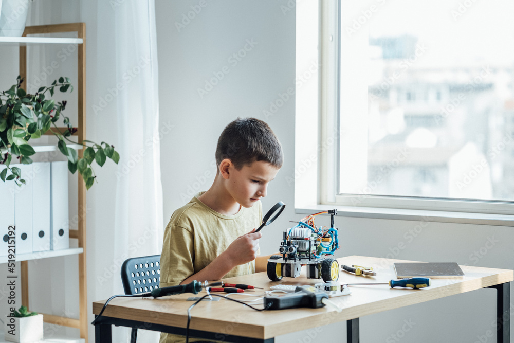 Engineering on develop of robot in laboratory. Smart positive boy testing robot while getting ready for engineering classes at home Engineering on develop of robot in laboratory. Smart positive boy testing robot while getting ready for engineering classes at home