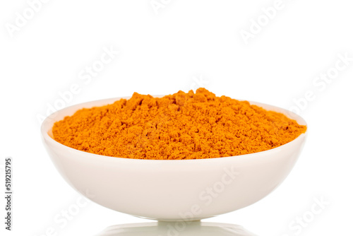 Aromatic bright yellow spice turmeric in a white ceramic saucer, close-up, isolated on a white background.