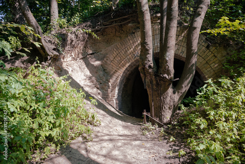 An old brick tunnel through an earthen hill. Ancient brick entrance to the dungeon