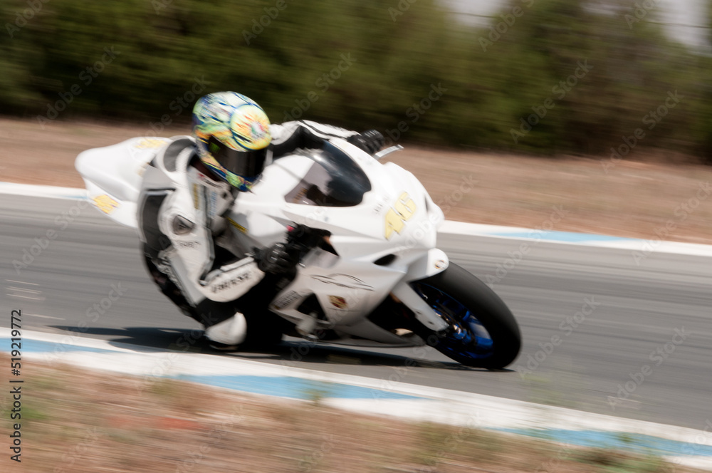 White sports motorcycle and rider racing fast on a track