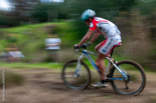 Cyclist pedalling in a racing mountain bike outdoors.  Unrecognized athlete on a bicycling race competition in motion © Michalis Palis