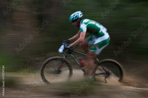 Cyclist pedalling in a racing mountain bike outdoors. Unrecognized athlete on a bicycling race competition in motion