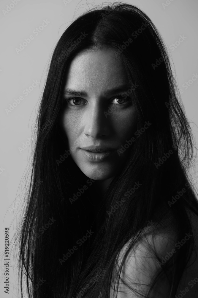 Close-up portrait of beautiful and sexy woman with long dark hair and eyes looking to the camera. Messy hair, mysterious and romantic mood. Model with naked shoulder and messy hair. Black and white im Close-up portrait of beautiful and sexy woman with long dark hair and eyes looking to the camera. Messy hair, mysterious and romantic mood. Model with naked shoulder and messy hair. Black and white im