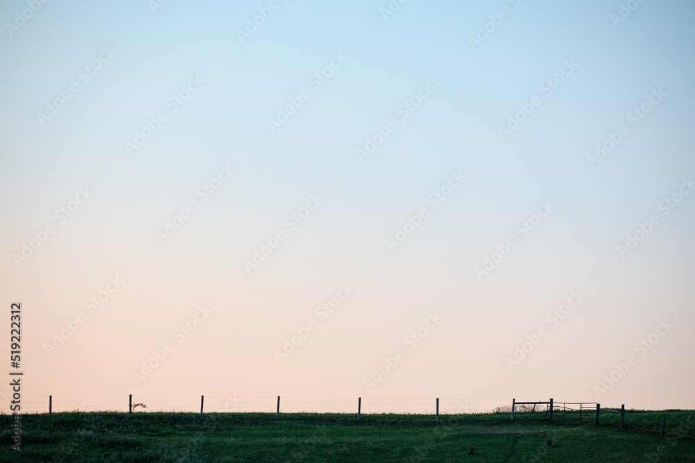 Pasture field with a fence on a hill under a pastel sky in the evening | farm land in Amish country, Ohio