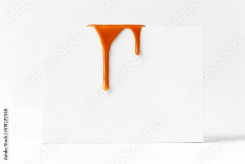 Dripping caramel drops of sweet caramel sauce on white podium on white background.  Melted caramel sauce drip, drops of sweet liquid toffee.