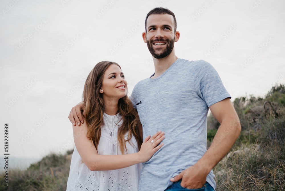 A Hispanic man is hugging his girlfriend in the highland park near sea in Spain