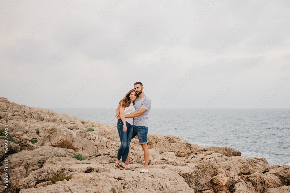 A man and his girlfriend are hugging on the rocky sea coast in Spain