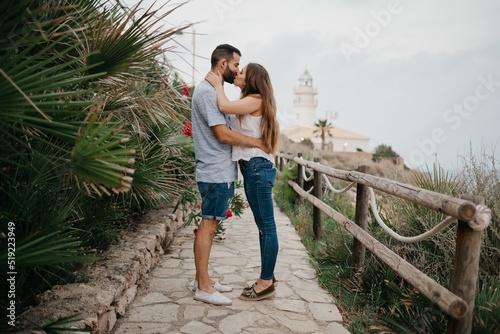 A man and his girlfriend are kissing on the path from a lighthouse in Spain