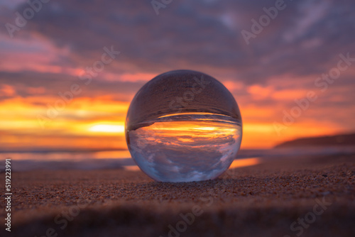 view of beautiful nature at sunset inside crystal ball..stunning sunset over sea in a crystal ball on the beach. .A image for a unique and creative travel..