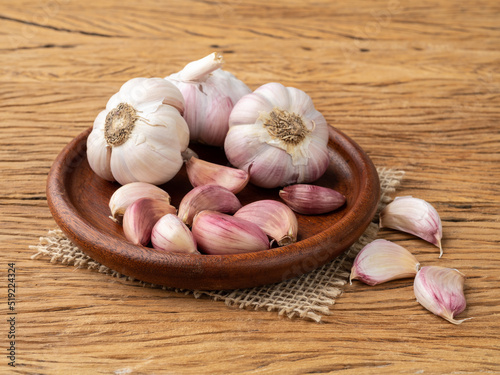 Garlic bulb and cloves on a plate over wooden table