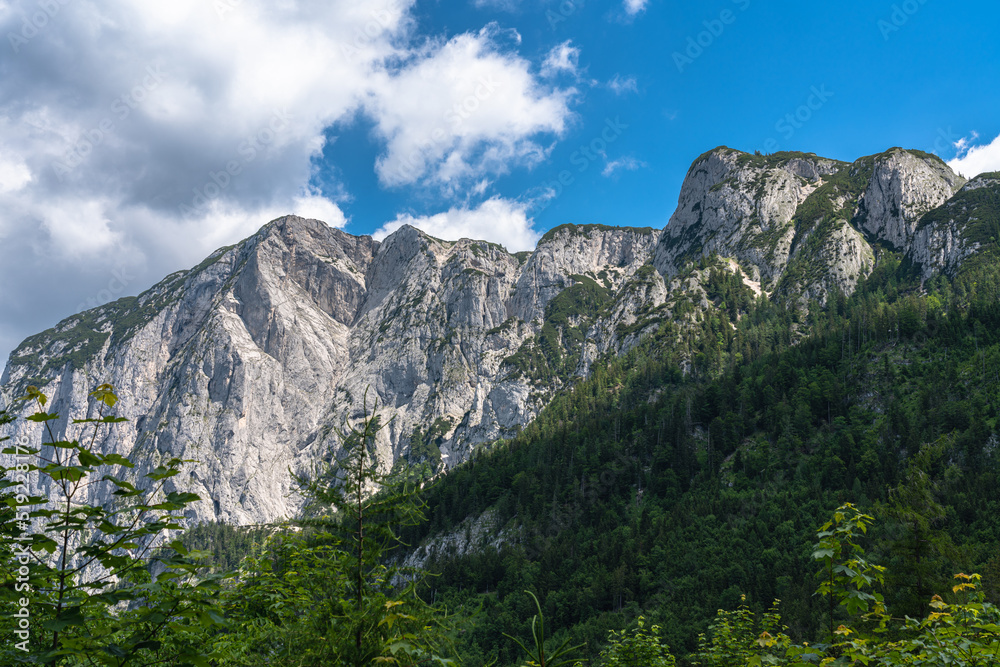 Stunning view of the steep cliff of Trisselwand above Altaussee lake on a sunny summer day with blue sky cloud, Salzkammergut-Ausseerland region, Styria, Austria