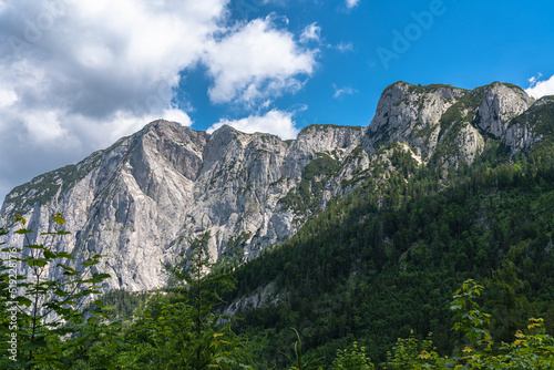 Stunning view of the steep cliff of Trisselwand above Altaussee lake on a sunny summer day with blue sky cloud, Salzkammergut-Ausseerland region, Styria, Austria