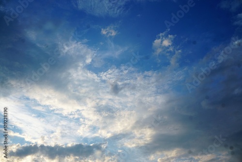 Blauer Himmel mit weißem dramatsichem Wolkengebilde bei Sonne am Abend im Sommer