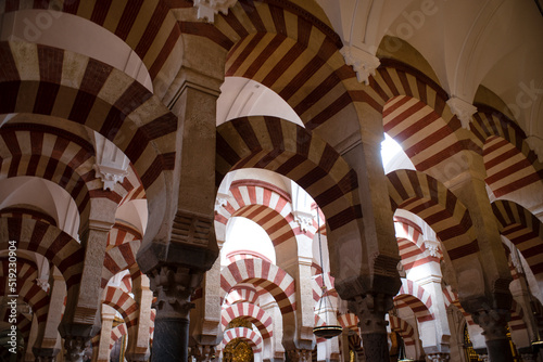 CÓRDOBA, SPAIN - APRIL, 2016. Arches Pillars Mezquita Cordoba Spain. Created in 785 as a Mosque, was converted to a Cathedral in the 1500. 850 Columns and Arches. Painted and striped arches. © John