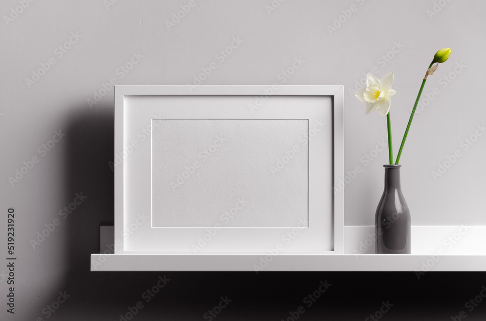 Landscape frame mockup on grey wall with flowers on white shelf Landscape frame mockup on grey wall with flowers on white shelf