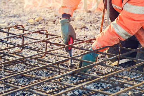 Φωτογραφία Builder's hands fixing steel reinforcement bars at construction site