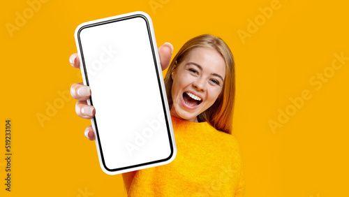 Laughing young woman showing mobile phone, mockup photo