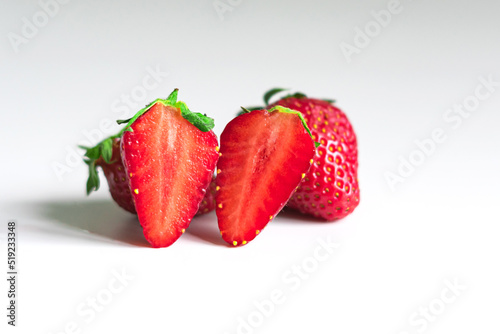 Close-up of a strawberry cut into two parts on a light background. The main strawberry are in focus, while the others in the background are out of focus.