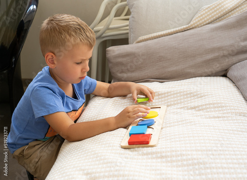 The child plays a wooden board game. Developing Montessori activities, the study of shapes and geometric shapes