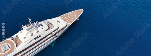 Aerial drone top down ultra wide photo with copy space of luxury mega yacht with wooden deck and helipad anchored in deep blue Aegean sea © aerial-drone