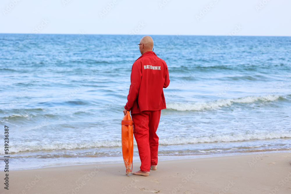 Ratownik na plaży podczas patrolowania brzegu wody nad morzem latem.  - obrazy, fototapety, plakaty 