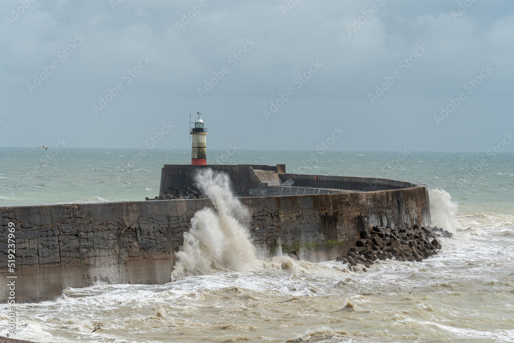 lighthouse and waves over a harbor arm