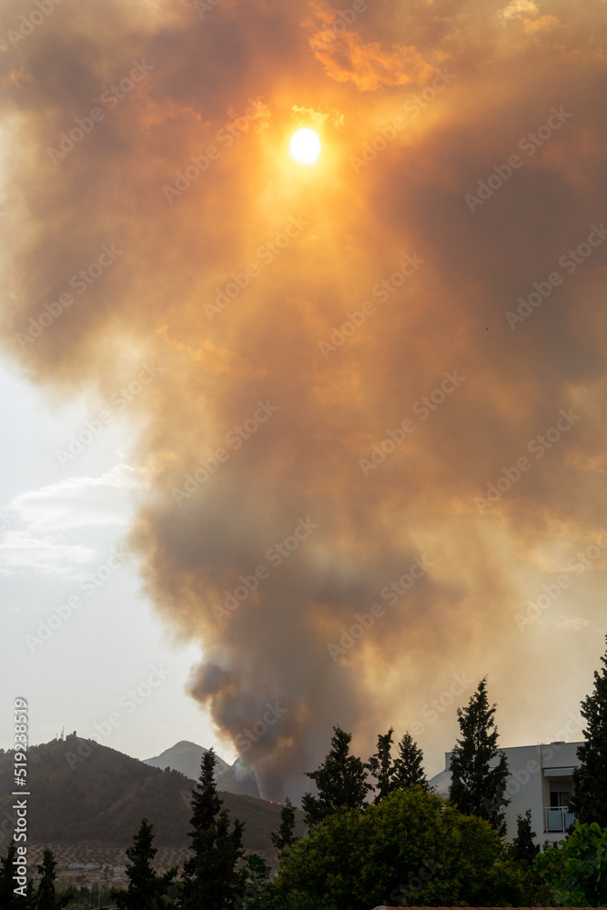 Large column of smoke that covers the sun due to a forest fire in mountains near several urbanizations of Albolote (Spain) in summer