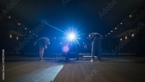 A troupe of actors with a woman with spinal muscular atrophy in a wheelchair coming out from the wings on the stage of the theater and bowing, during a rehearsal with the director © Framestock