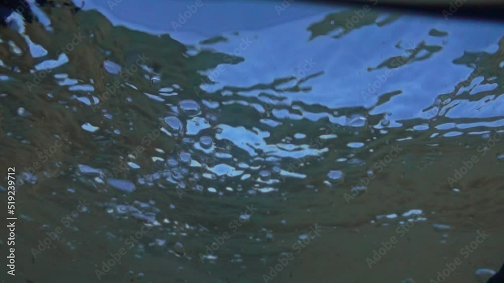 The camera plunges under the water and the ocean waves above it.